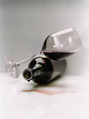 an empty wine glass sitting on top of a white table next to a red wine bottle