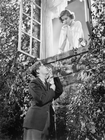 an old black and white photo of a woman in front of a window looking up