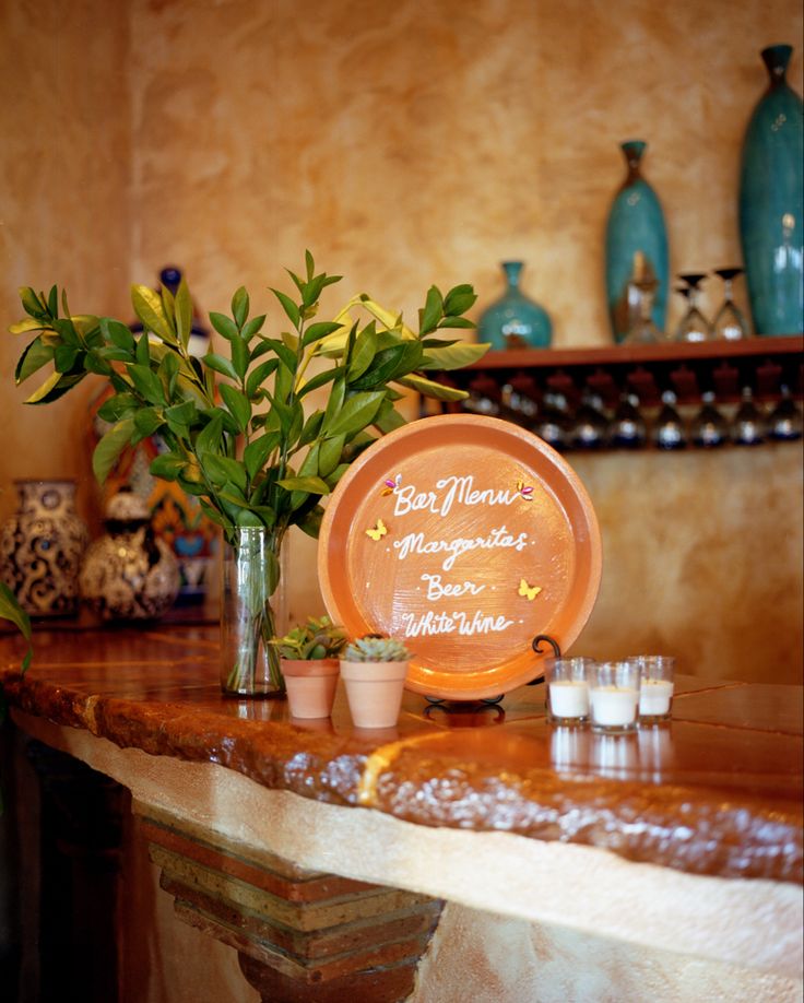 an orange plate sitting on top of a table next to two vases filled with plants