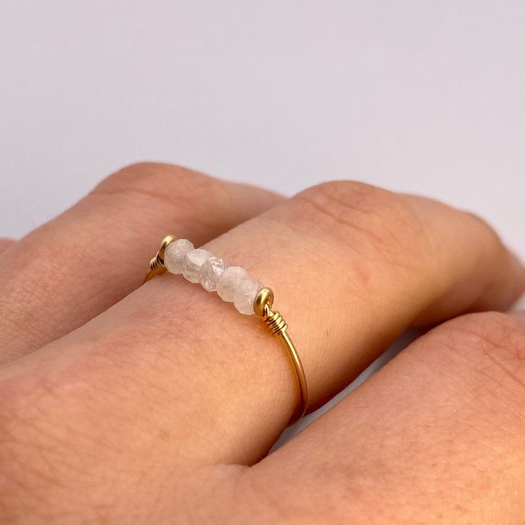 This beautifully simple ring is lovingly handmade with 5 tiny Moonstones and a choice of 14k Gold Filled, 14k Rose Gold Filled or Sterling Silver band. M A T E R I A L S: * Rainbow Moonstone * 14k Gold Filled, 14k Rose Gold Filled or Sterling Silver S I Z E: *  Gemstone - Approximately 2mm each *  Band Thickness - Approximately 0.8-1mm  All of our jewellery is carefully handmade using good quality materials and handpicked gemstones, with the aim to produce quality pieces that you can love & wear Dainty Gemstone Midi Rings For Everyday, Dainty Everyday Midi Rings With Gemstones, Dainty Handmade Midi Rings For Anniversary, Dainty Everyday Stackable Moonstone Ring, Handmade 14k Gold Crystal Promise Ring, Handmade Delicate 14k Gold Filled Rings, Handmade 14k Gold Crystal Ring For Promise, Dainty Handmade Stackable Rings For Anniversary, Dainty Everyday Moonstone Ring