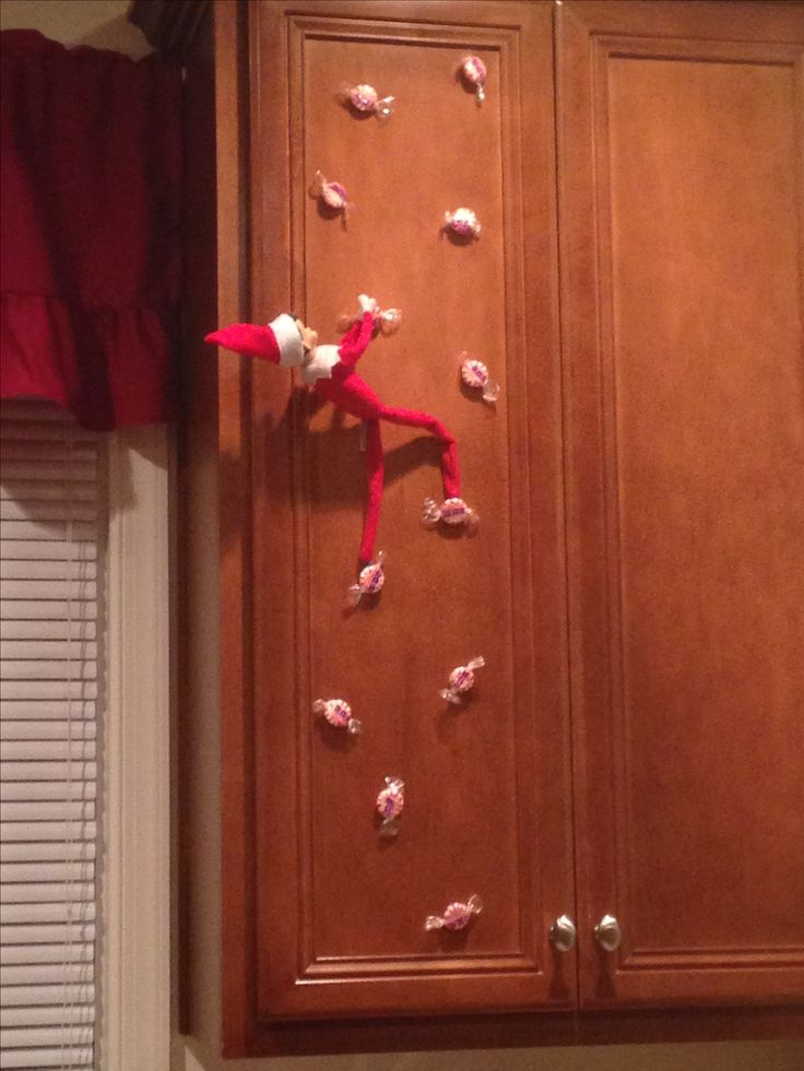 an elf on the shelf with candy in front of it and some stickers on the door