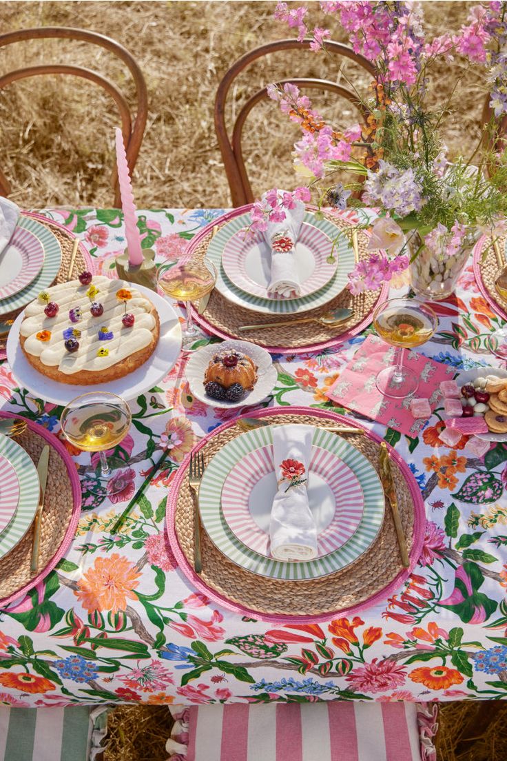 a table set with plates and desserts on it in the middle of a field