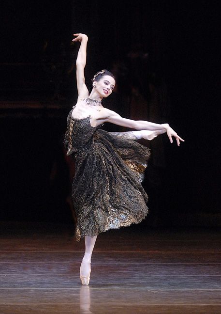 a ballerina in black and gold dress on stage