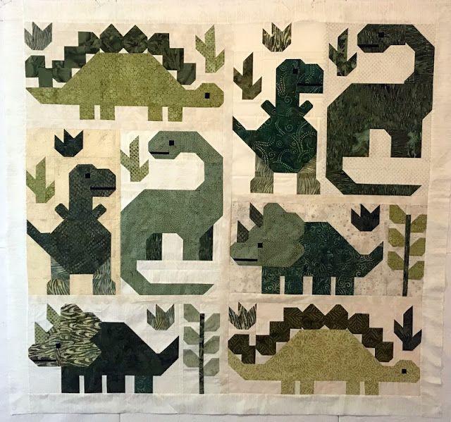 a quilted wall hanging with dinosaurs on it