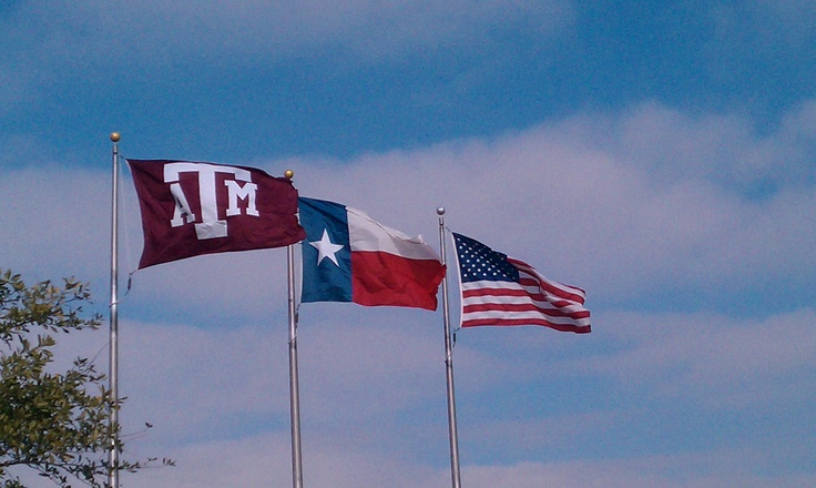 three texas and texas state flags flying in the wind