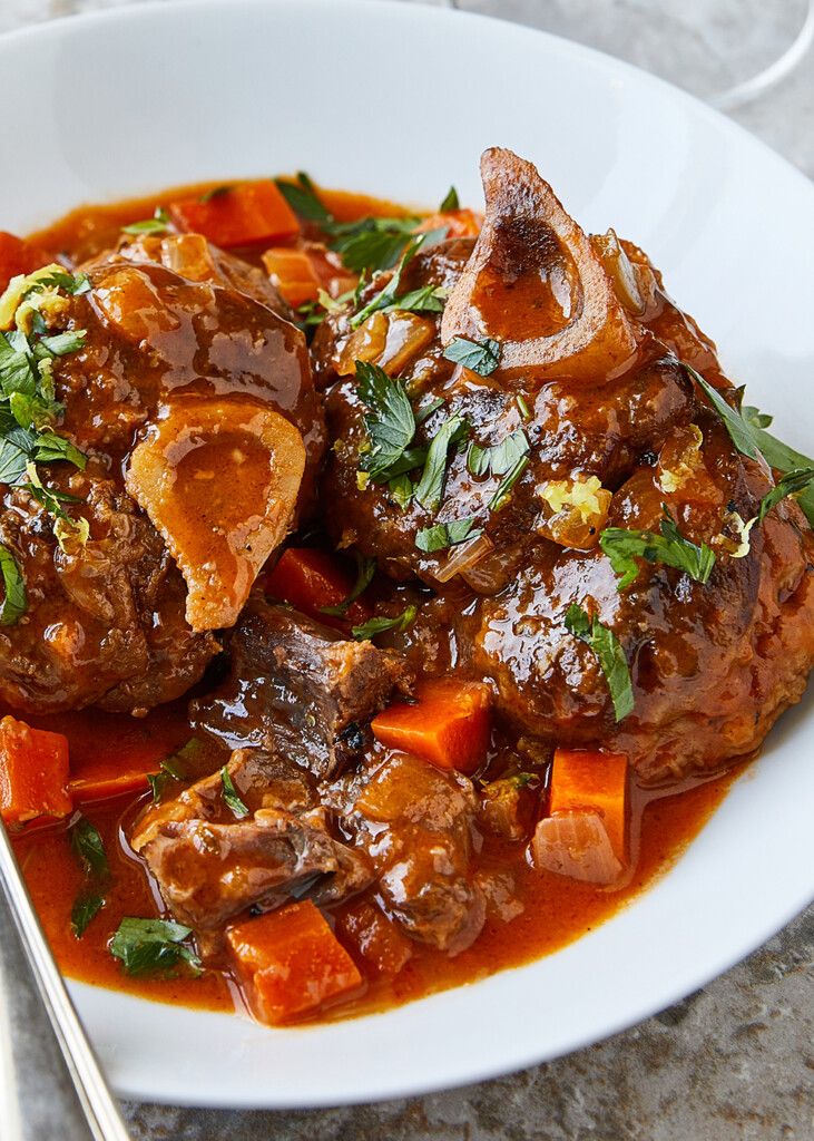 a white plate topped with meat covered in gravy and carrots next to a fork