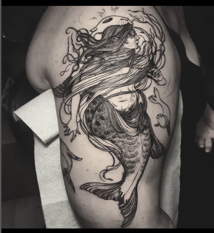 a black and white photo of a woman with a fish tattoo on her thigh,