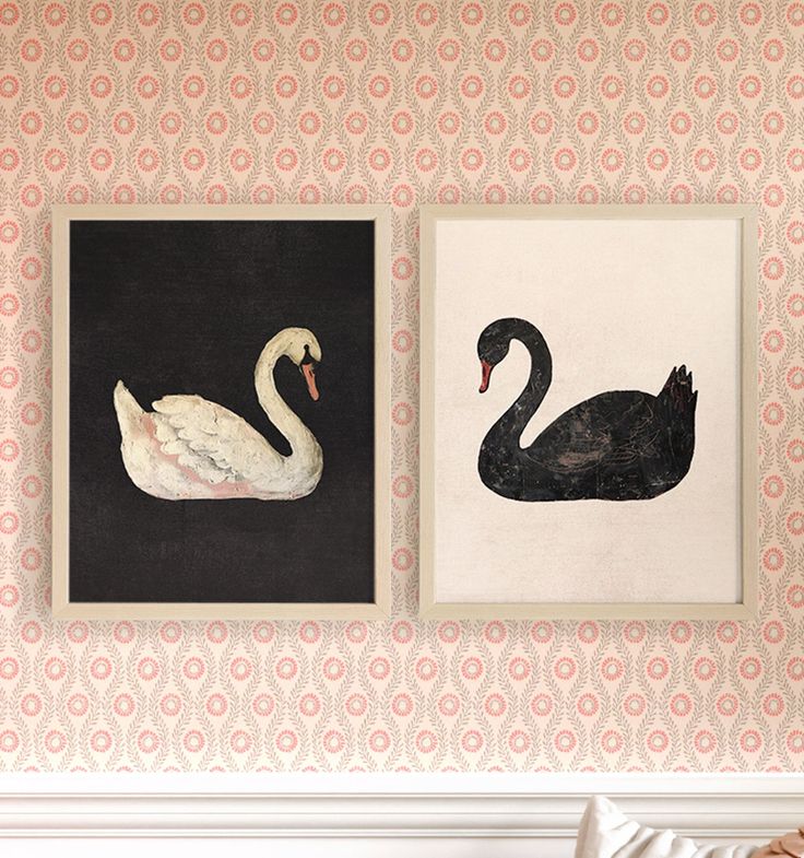 two black and white swans are hanging on the wall next to each other in a bedroom