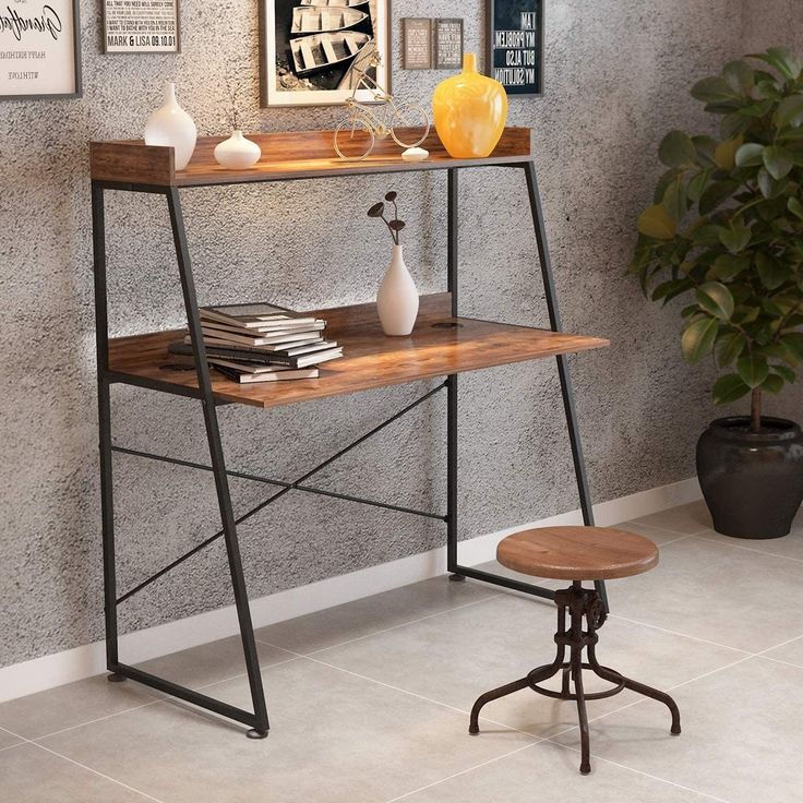 a desk with a wooden top and metal frame, sitting in front of a gray wall