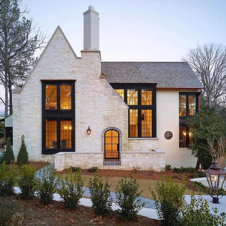 a white brick house with large windows at dusk