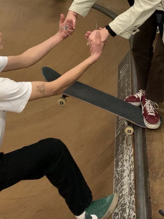 two people holding hands while standing on a skateboard ramp