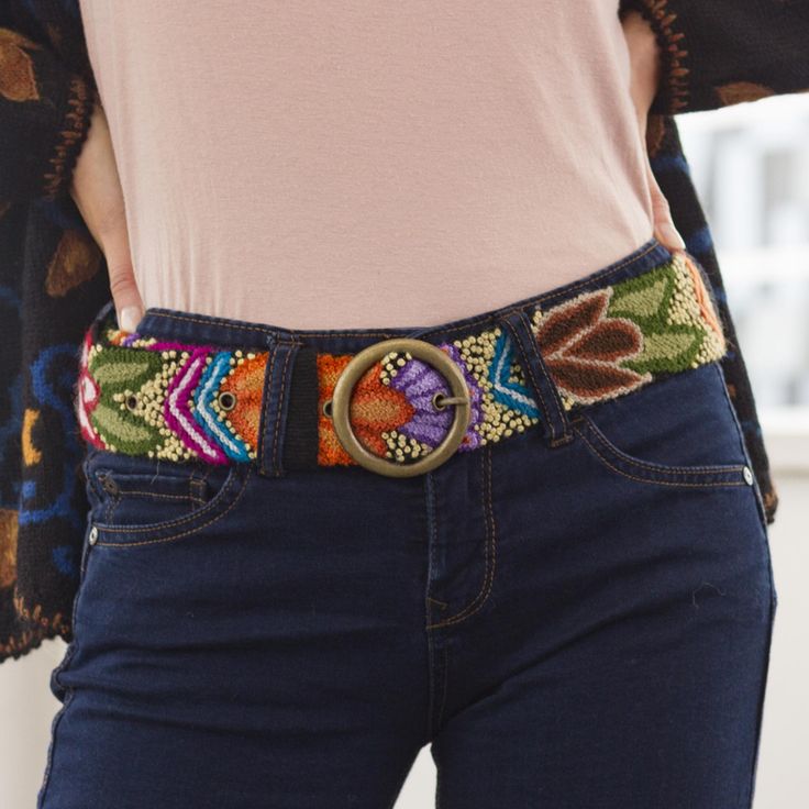 a woman is wearing a colorful belt with a ring on the front and side of her waist