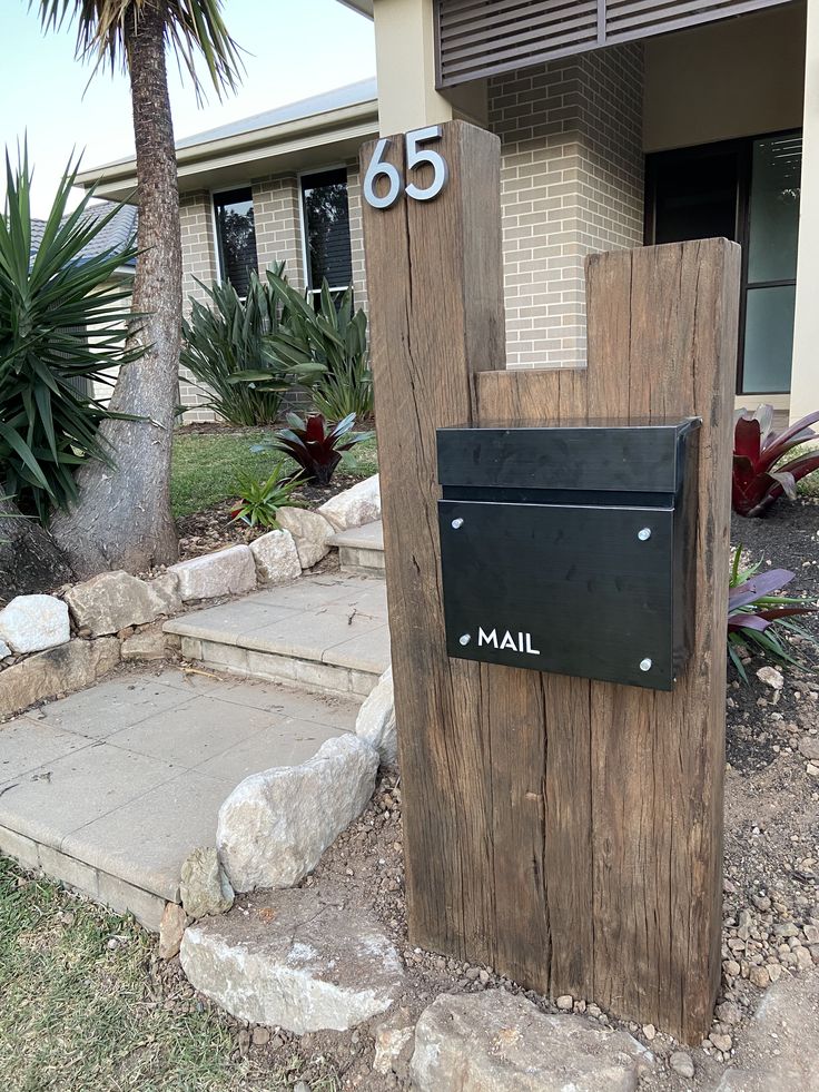 the mailbox is made out of wood and has metal numbers on it's side