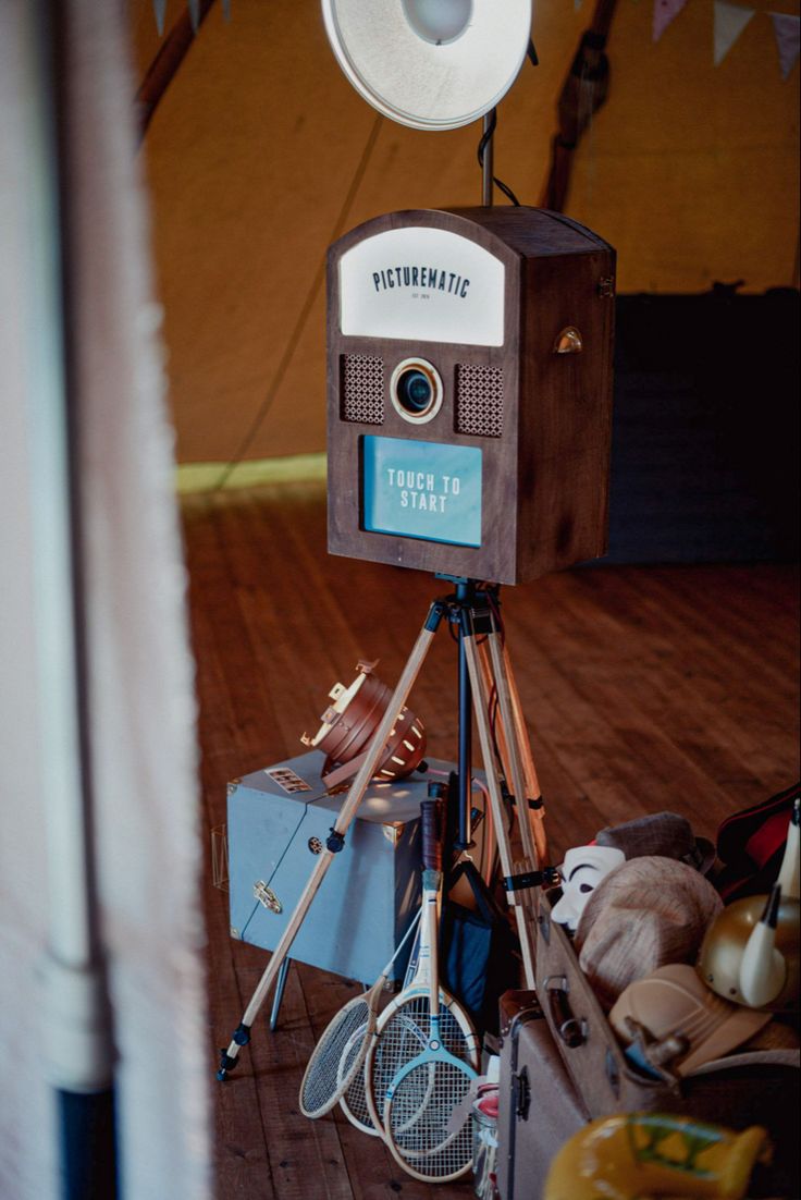 an old fashioned camera sitting on top of a tripod with tennis rackets and racquets