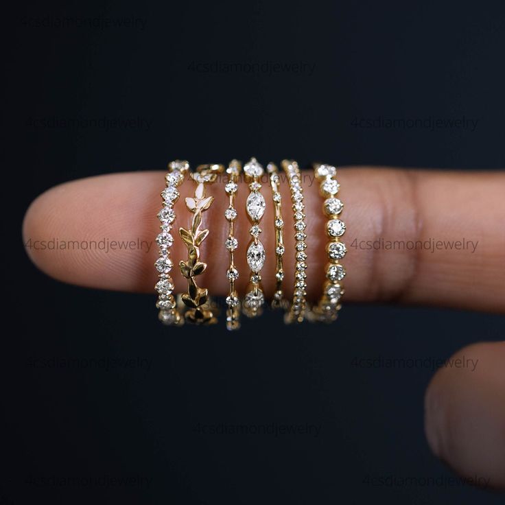 a woman's hand with five gold rings on it and four diamond bracelets