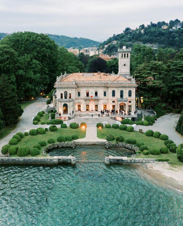 an aerial view of a large house with trees and bushes around it on the water