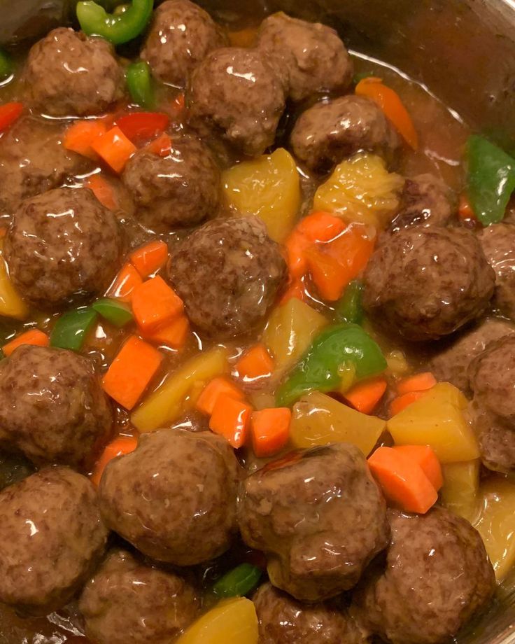 meatballs, carrots and peppers are in a pot with broth on the side