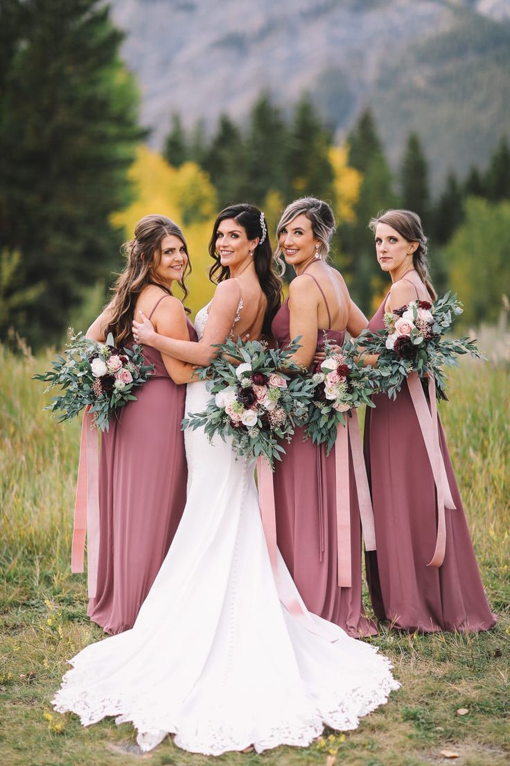 the bride and her bridesmaids pose for a photo in front of some mountains