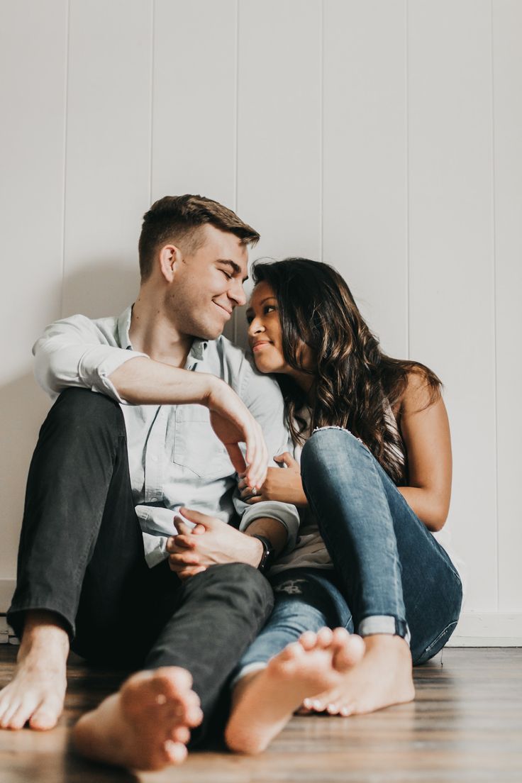 a man and woman sitting on the floor looking at each other's foreheads