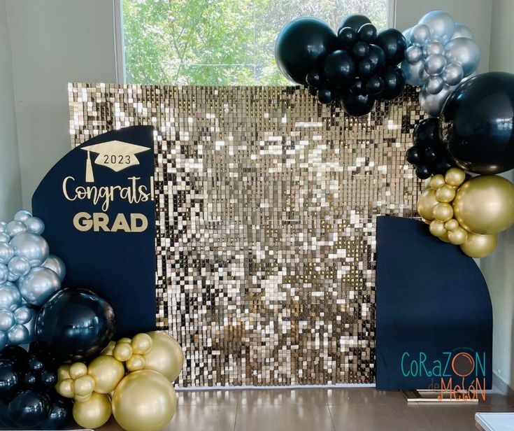 graduation decorations and balloons are displayed on a table in front of a backdrop that reads congratulations grad