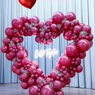 a heart shaped balloon with the word love spelled in white letters and surrounded by pink balloons