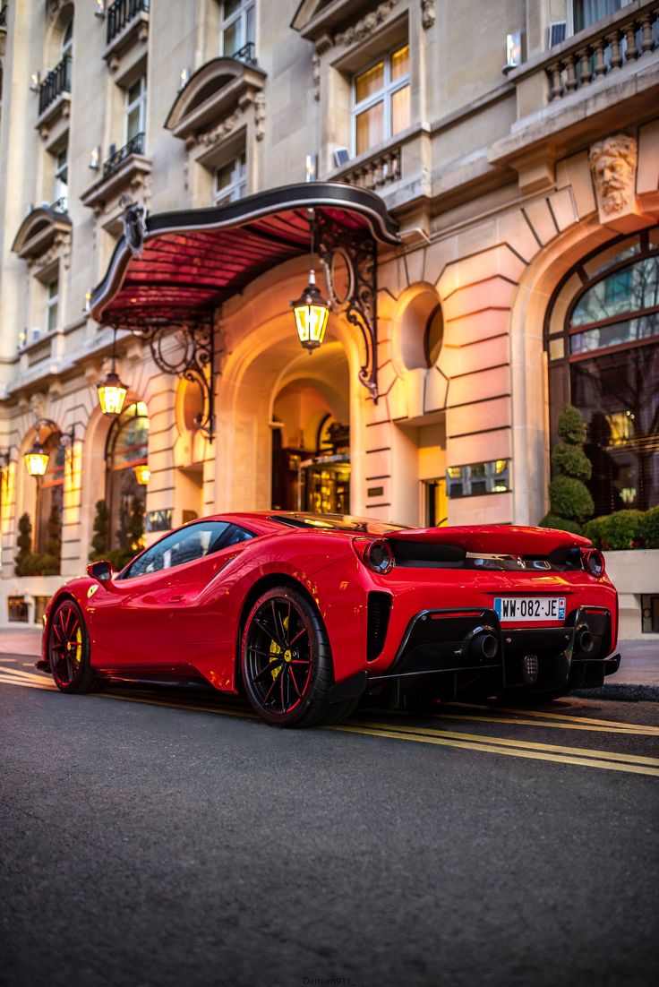 a red sports car is parked in front of a building with lights on the side