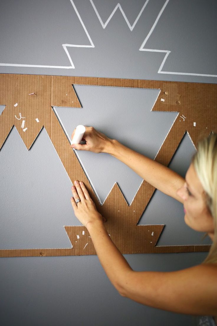 a woman is painting a wall with white paint and she has her hands on the board