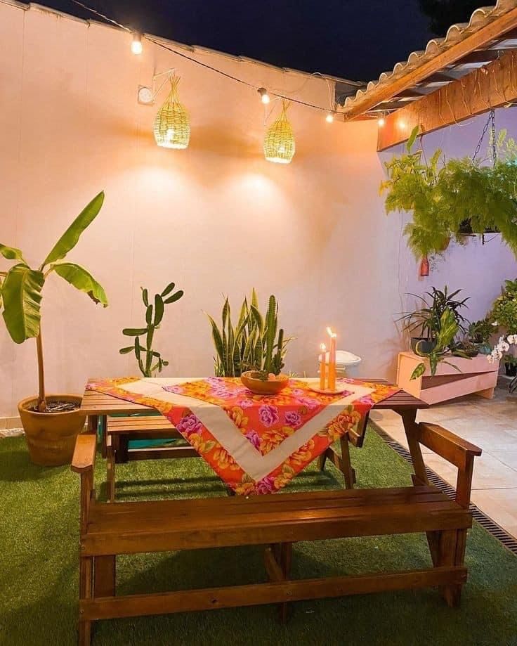 a table with candles on it sitting in the middle of a patio area surrounded by potted plants