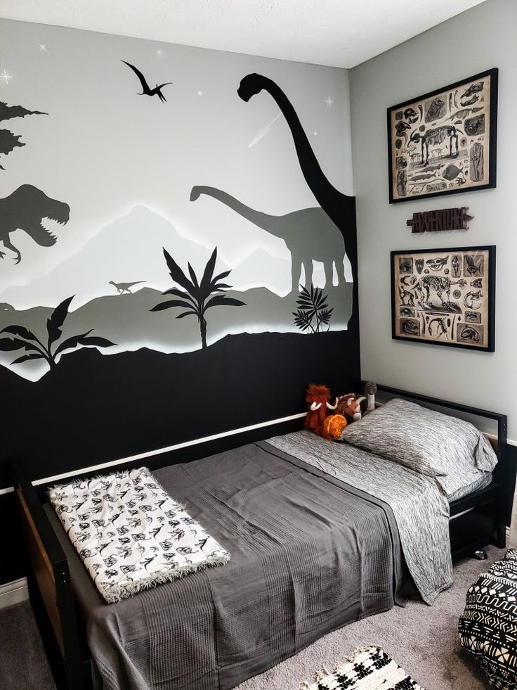 a bedroom decorated in black and white with dinosaurs on the wall