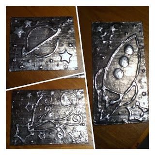 three metal pieces with designs on them sitting on top of a wooden table next to each other