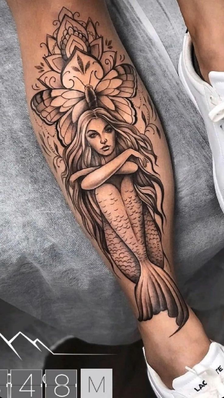 a woman's leg with a tattoo on it and an image of a mermaid