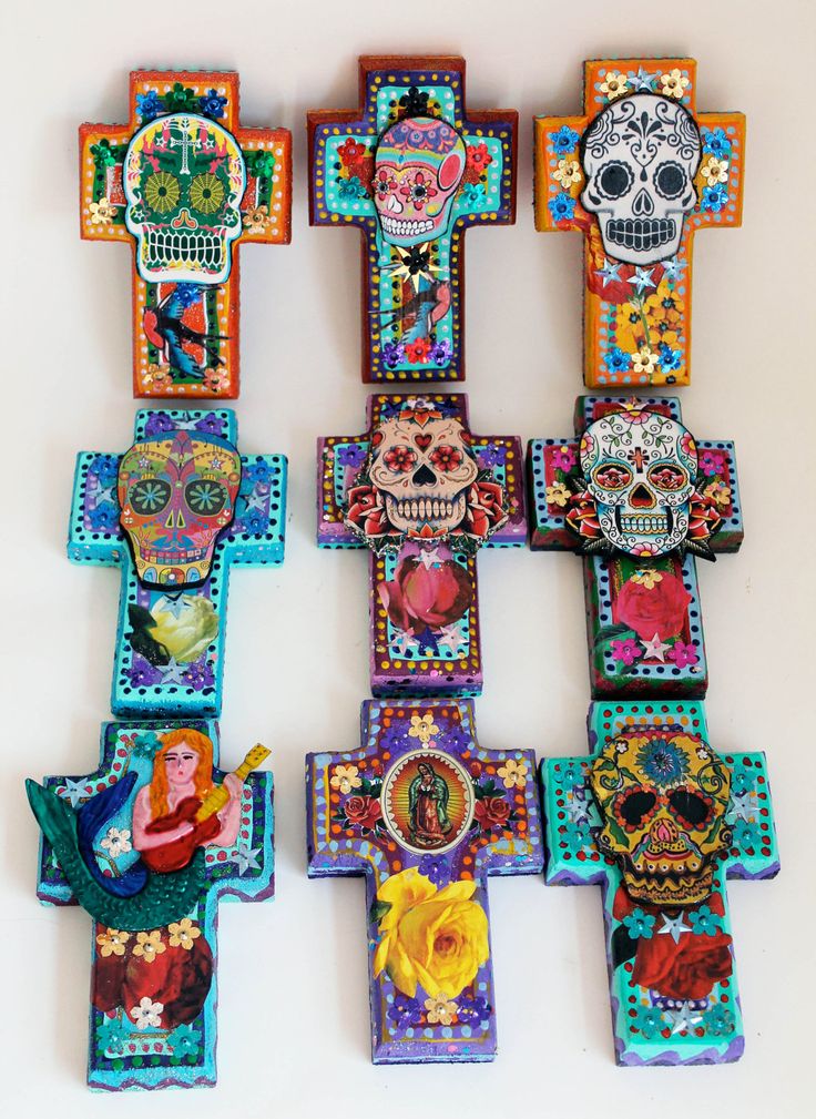 a group of colorful crosses with skulls and flowers on them