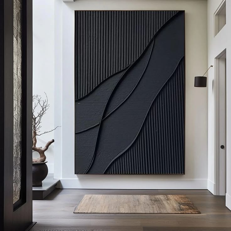 a large black piece of art hanging on the wall next to a rug in a room