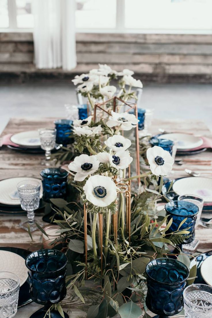 the table is set with blue and white plates, silverware, and anemone centerpiece