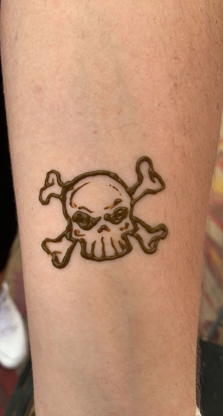 a skull and crossbones tattoo on the left calf area of a person's leg