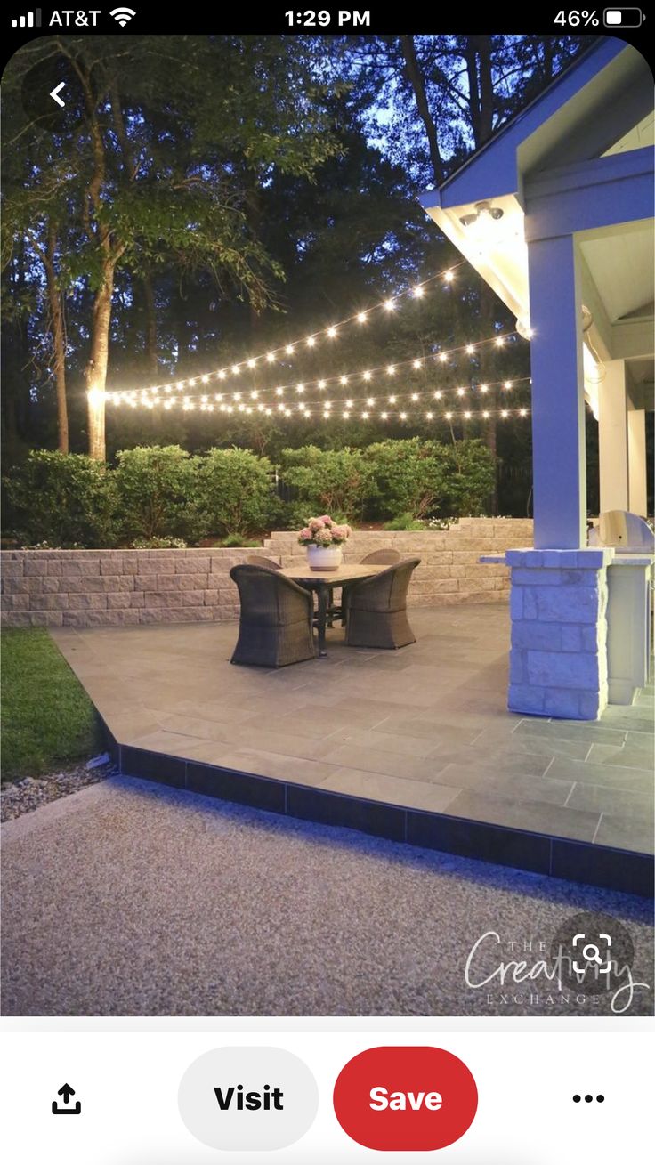 an outdoor dining area with string lights strung over the table and chairs on the patio