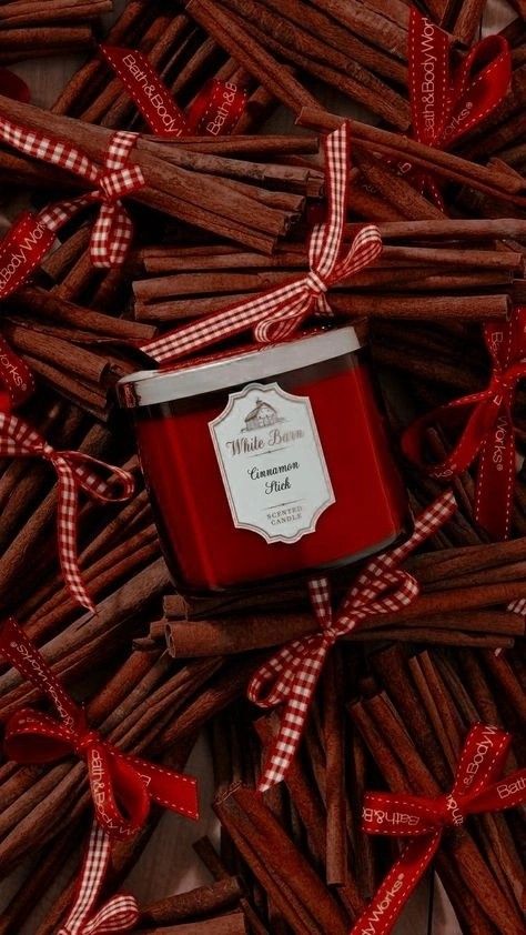 a red candle sitting on top of a pile of brown sticks with ribbon around it