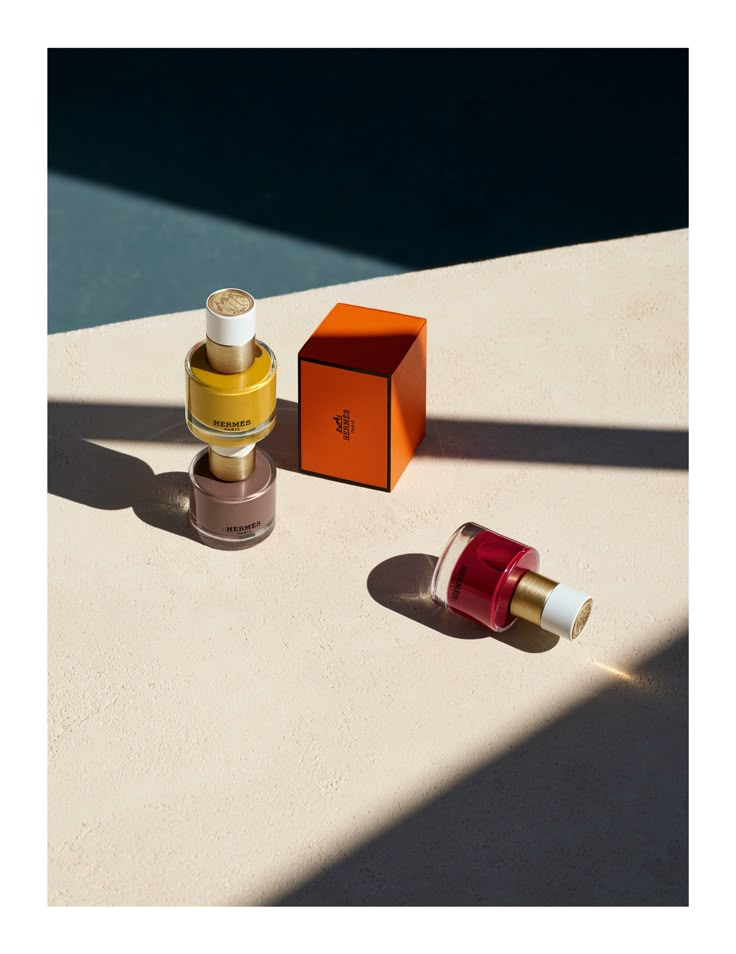 two bottles of perfume sitting on top of a table next to an orange and white box