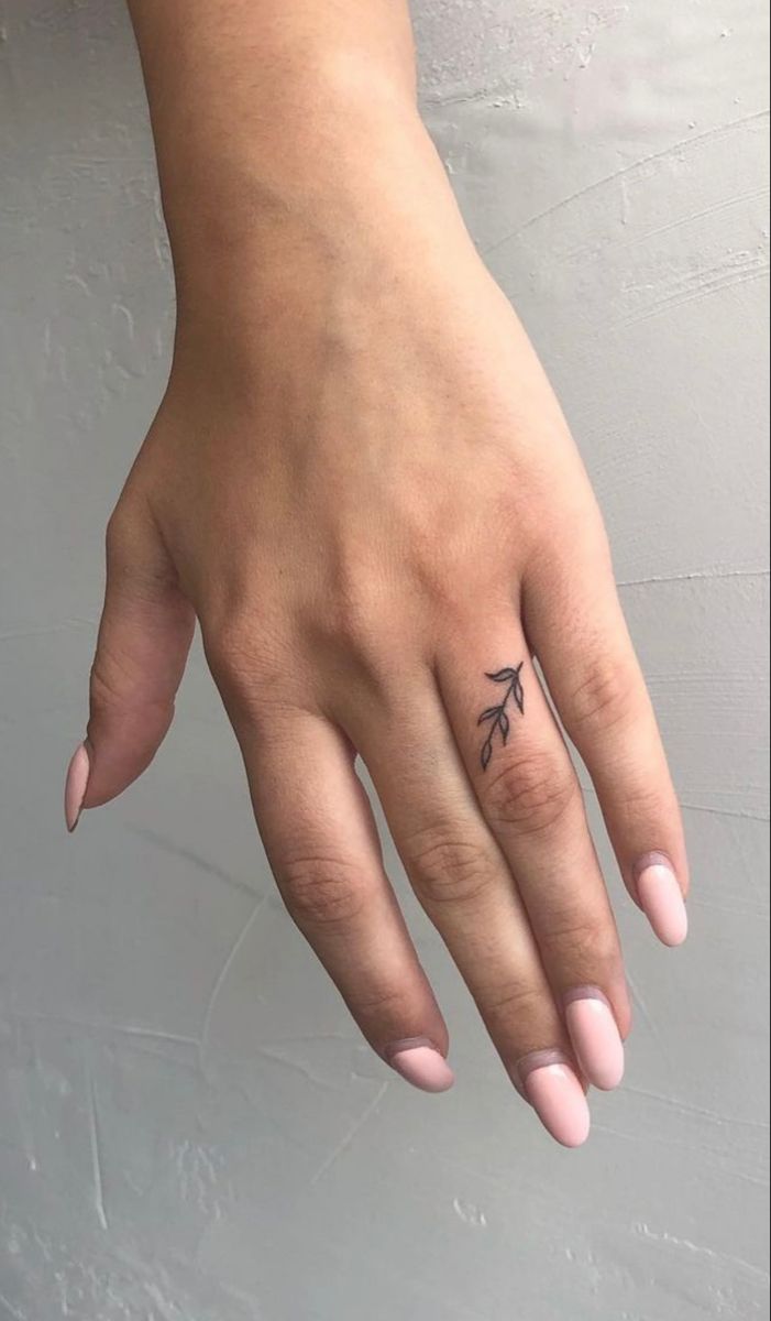 a woman's hand with a small tattoo on it, and the ring finger