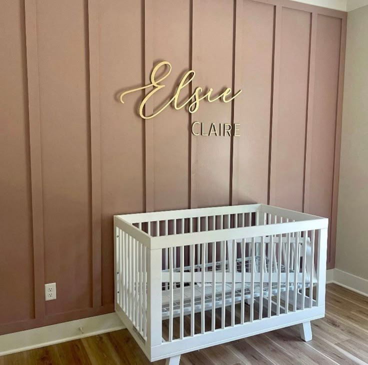 a white crib in front of a pink wall with the name elsie written on it