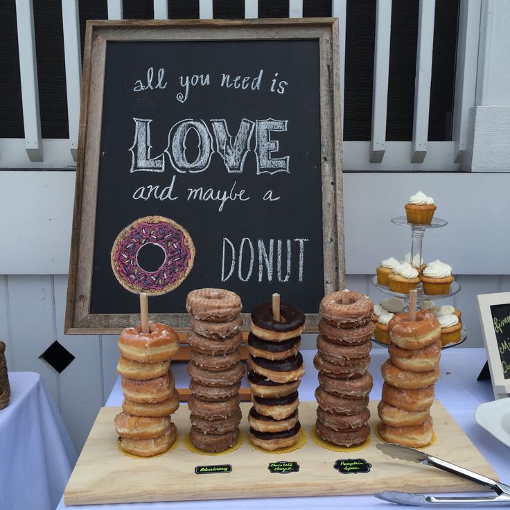 donuts are stacked on top of each other in front of a sign that says, all you need is love and maybe doughnuts