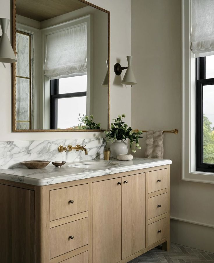 a bathroom with marble counter tops and two sinks in front of a large mirror above the sink