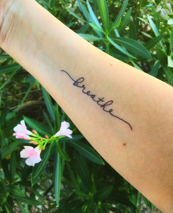 a woman's arm with the word breathe written on it in cursive handwriting