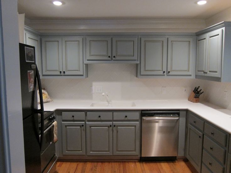 a kitchen with gray cabinets and white counter tops