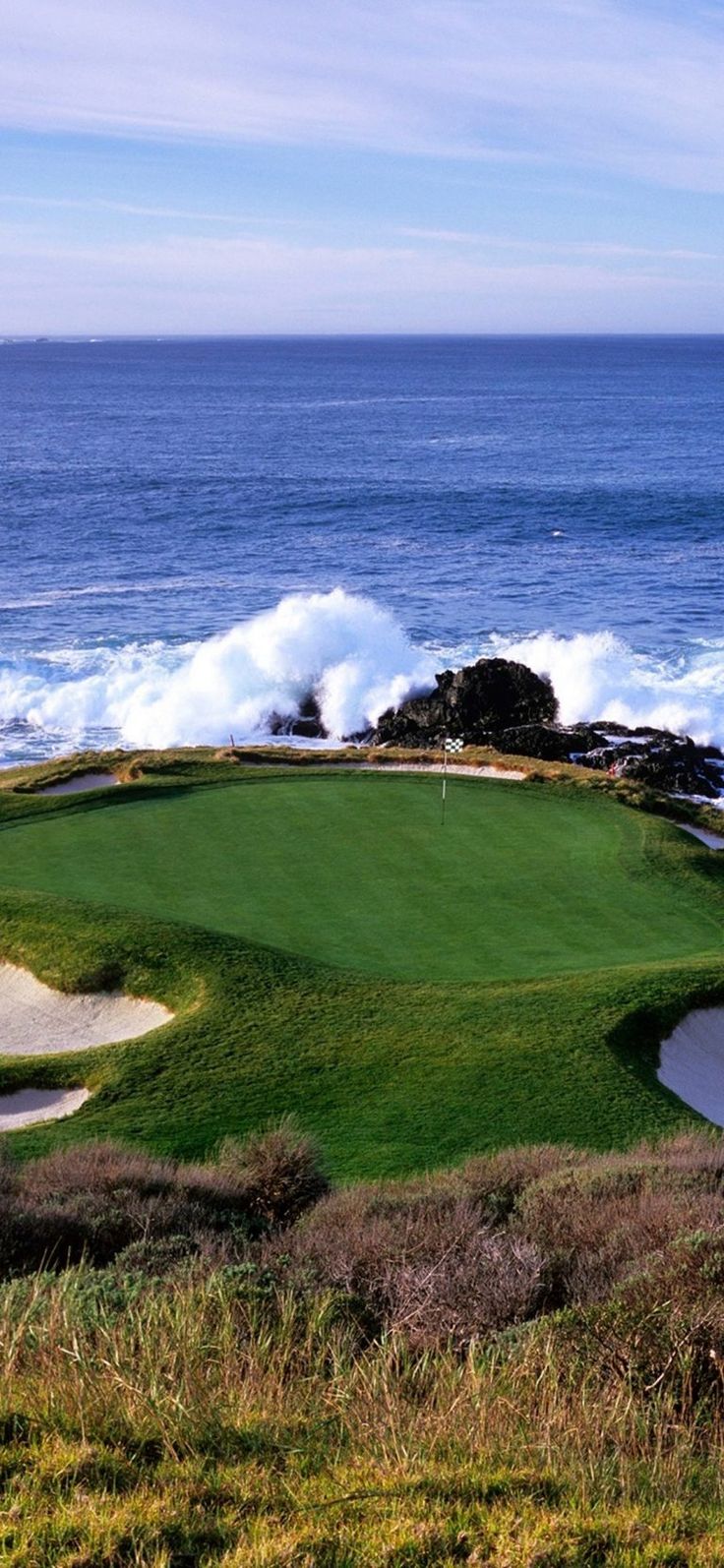 a golf course near the ocean with waves coming in from the water and on to the green