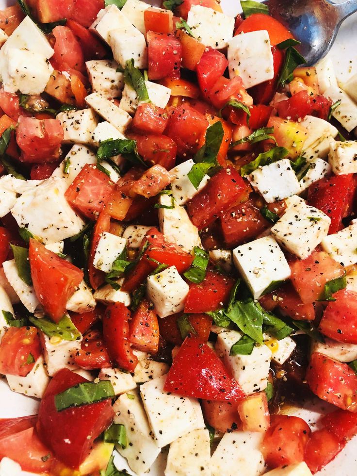 a salad with tomatoes, mozzarella and basil on it is ready to be eaten