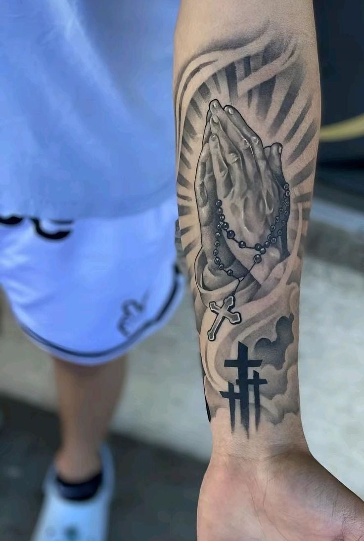 a person with a tattoo on their arm holding a rosary and cross in his hand