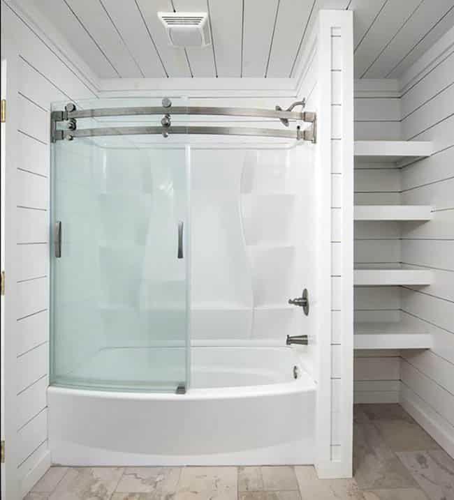 a walk in shower sitting inside of a bathroom next to a white shelf filled with shelves