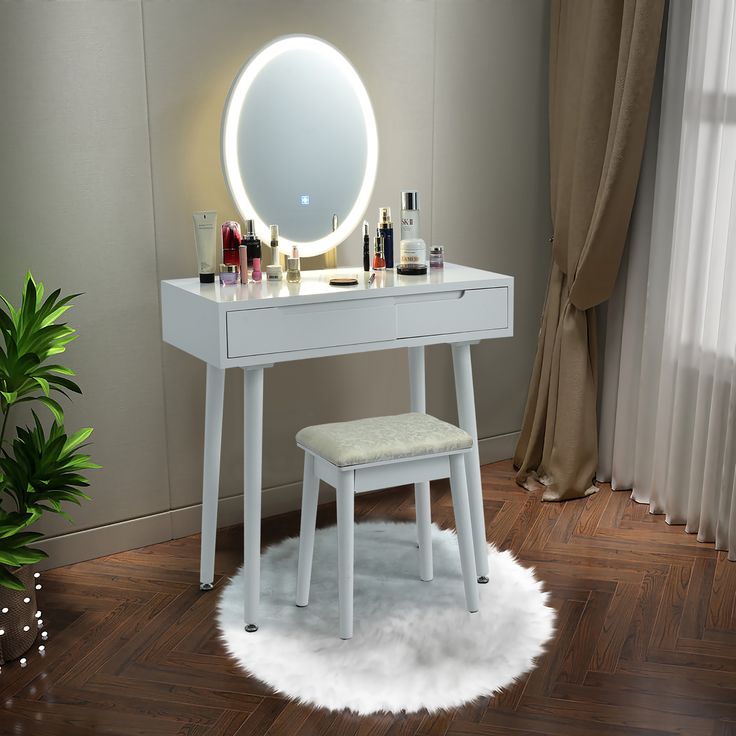 a white vanity table with a stool and lighted mirror on it in front of a window