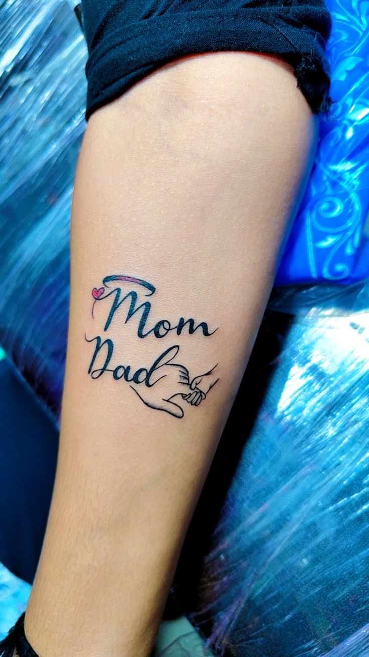 a woman with a tattoo on her leg that says mom and dad in cursive writing